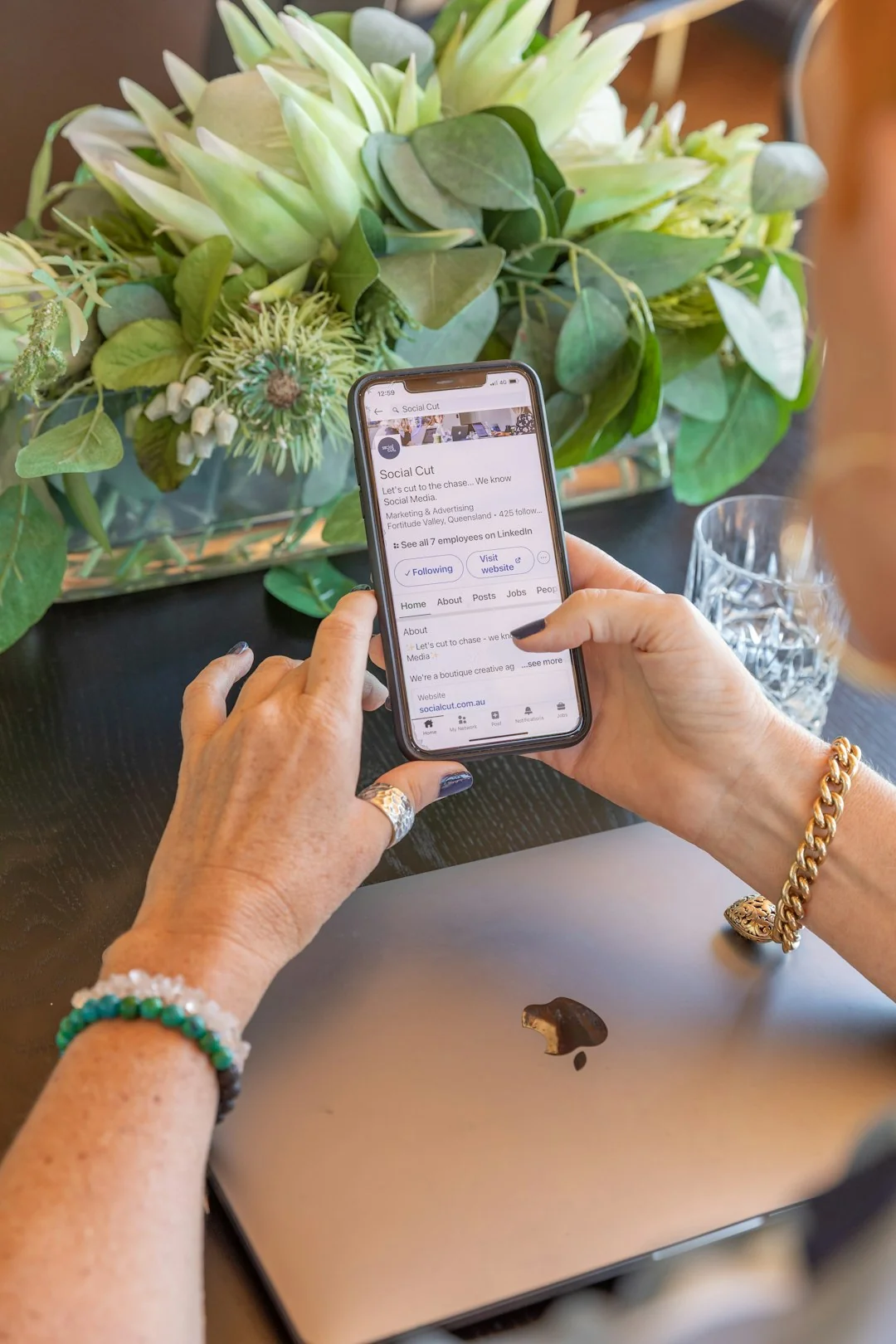 Personne analyse des données boursières avec un smartphone et un ordinateur portable, en intérieur.